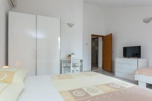 een witte slaapkamer met een bed en een televisie bij Villa Anka in Cavtat