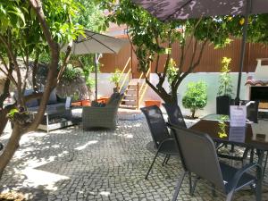 un patio con sillas, mesas y una sombrilla en HOTEL BOUTIQUE a ESPLANADA, en Castelo Branco