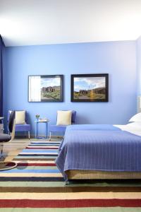 1 dormitorio con paredes azules, 1 cama y sillas en The Editory House Ribeira Porto Hotel, en Oporto
