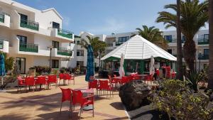 a group of tables and chairs in front of a hotel at Lanzarote-Beach-Apartment, Las Cucharas Beach, Costa Teguise -- 1 MINUTE WALK FROM MAIN SQUARE, 35 METERS FROM BEACH in Costa Teguise