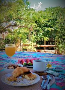una mesa con un plato de comida y un vaso de zumo de naranja en Mambo Ecohostal, en San Lorenzo