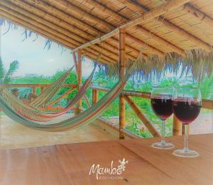 two glasses of red wine on a table with a hammock at Mambo Ecohostal in San Lorenzo