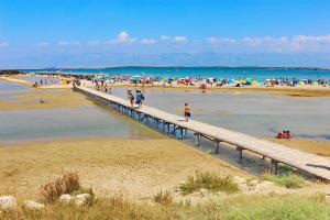 a group of people on a beach with a pier at Apartmani Danijel in Nin