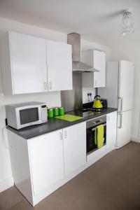a kitchen with white cabinets and a microwave at Alphalink Apartment in Middlesbrough