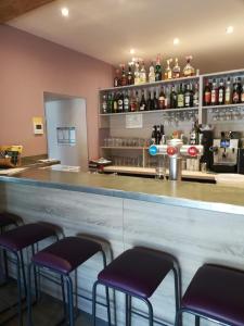 a bar with purple stools in front of a counter at Hôtel de la Poste Chez Cécile in La Grande-Verrière