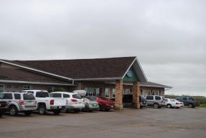 un estacionamiento con autos estacionados frente a un edificio en Moosomin Country Squire Inn, en Moosomin