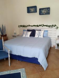 um quarto com uma grande cama branca e uma cadeira azul em Casa Petros em Marsala