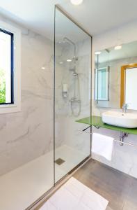 a bathroom with a glass shower and a sink at Duerming O Casal da Martiña in Poio