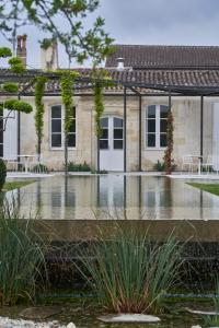 a house with a pond in front of it at CHASSE-SPLEEN Les Chambres in Moulis-en-Médoc