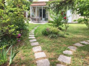 un jardin avec un chemin en pierre en face d'une maison dans l'établissement Le Cèdre Bleu, à Fouras