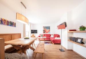 een woonkamer met een tafel en een rode bank bij Appartements Ausserladscheider in Leutasch