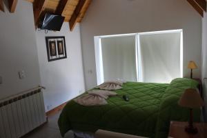 a bedroom with a green bed and a large window at Hotel Arquimedes in Caviahue