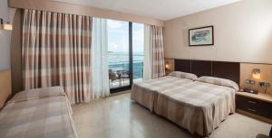 
a hotel room with a large bed and a large window at Hotel Flamingo in L'Ampolla
