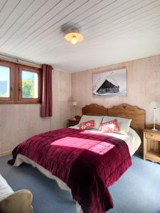 a bedroom with a large bed with a red blanket at Chalet Le Renard Du Lac in Les Gets