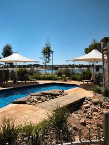 a swimming pool with umbrellas and chairs and a patio at Majestic Oasis Apartments in Port Augusta