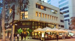 un edificio con sombrillas y gente caminando delante de él en Hotel Diego de Velazquez, en Santiago