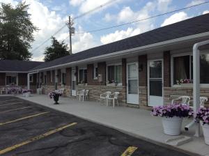 a building with white chairs and tables and purple flowers at Tay Inn in Perth