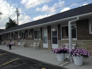 a building with tables and chairs and purple flowers at Tay Inn in Perth