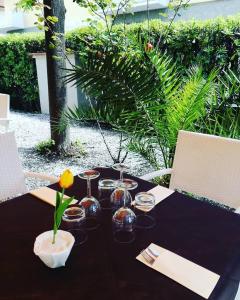 un tavolo nero con gli occhiali e un vaso sopra di Hotel Giulia a Marina di Massa