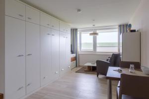 a kitchen with white cabinets and a table and chairs at Strandhaus Christiansen in Cuxhaven