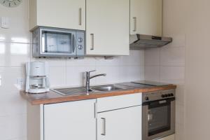 a kitchen with white cabinets and a sink and a microwave at Strandhaus Christiansen in Cuxhaven