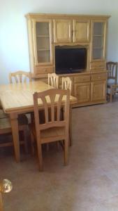 a wooden dining room table with chairs and a television at Casas Valleiruelas in Las Cruceras