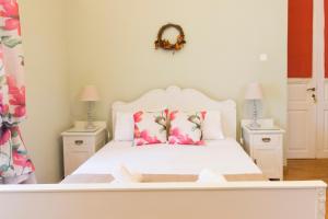 sypialnia z białym łóżkiem i różowymi kwiatami w obiekcie Ermoupolis 1834 Classic beauty w mieście Ermupoli