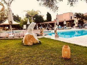 a statue of a bird sitting on a rock next to a pool at Hotel Oasi da Paolo in Castelluzzo