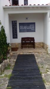 un banco frente a un edificio con un cartel en Peniche Blue Wave Home, en Peniche