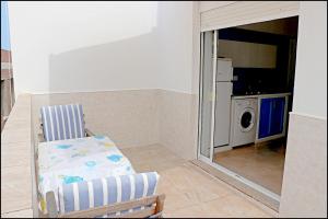 Apartamento con terraza في كونيل دي لا فرونتيرا: غرفة بها كرسي وغسالة ومجفف