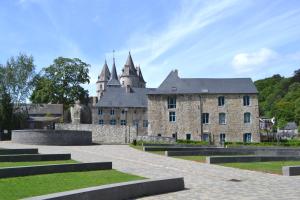 an old stone building with a castle in the background at Les Roques Apartments in historical Monastery in Durbuy