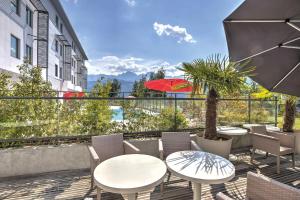 a patio with tables and chairs and a balcony with a view at Appart'City Confort Grenoble Inovallée in Montbonnot-Saint-Martin