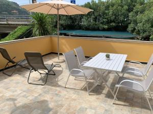 una mesa, sillas y una sombrilla en el patio en Affittacamere Sapore di Mare, en Levanto