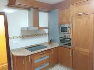 kuchnia z drewnianymi szafkami i kuchenką z piekarnikiem w obiekcie Apartamento La Real w mieście Caldas de Reis