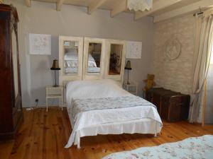 a bedroom with a large white bed and wooden floors at Le vieux Prieuré in Cressé