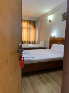 a bedroom with two beds and a red tag on a door at Hotel Jc Grand in Kodaikānāl