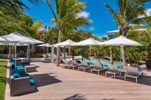 格雷斯灣的住宿－The Oasis at Grace Bay，度假酒店的游泳池配有椅子和遮阳伞