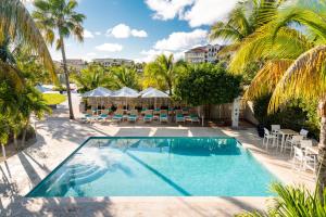 a pool with chairs and tables and palm trees at The Oasis at Grace Bay in Long Bay Hills