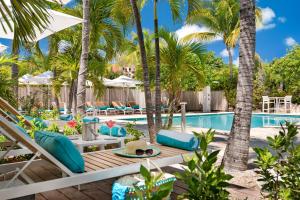 a resort pool with palm trees and lounge chairs at The Oasis at Grace Bay in Grace Bay