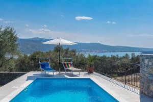 a swimming pool with two chairs and an umbrella at Holiday house Ledine -Kornić, Krk in Kornić
