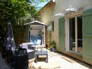 un patio con mesa, sillas y sombrilla en Les Chênes Verts en Valbonne