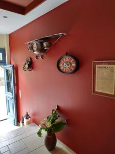 a red wall with a ceiling fan and a clock at Xenonas Afroditi in Loutra