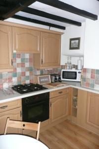 cocina con armarios de madera y horno con fogones en Pat's Cottage, en Sheffield