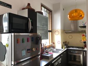 eine Küche mit einem Kühlschrank aus Edelstahl und einer Mikrowelle in der Unterkunft Bnbook-Tommaso Grossi Rho Fiera in Rho