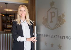 a woman is standing in front of a sign at Hotel Post Sindelfingen in Sindelfingen