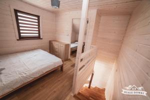 a small bedroom with a bed and a window at Białe Domki Mrzeżyno, wypoczynek w ciszy i zieleni in Mrzeżyno
