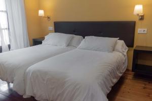 a bedroom with a large bed with white sheets and pillows at Apartamentos San Roque in Llanes