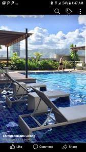 a picture of a swimming pool with a man walking in the water at KC Studio 1 at Horizons 101 Cebu in Cebu City