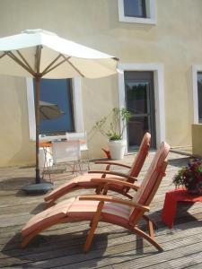 two lounge chairs and an umbrella on a deck at La Chambre du Meunier in Laiz