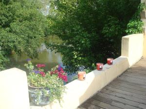 a retaining wall with pots of flowers next to a river at La Chambre du Meunier in Laiz